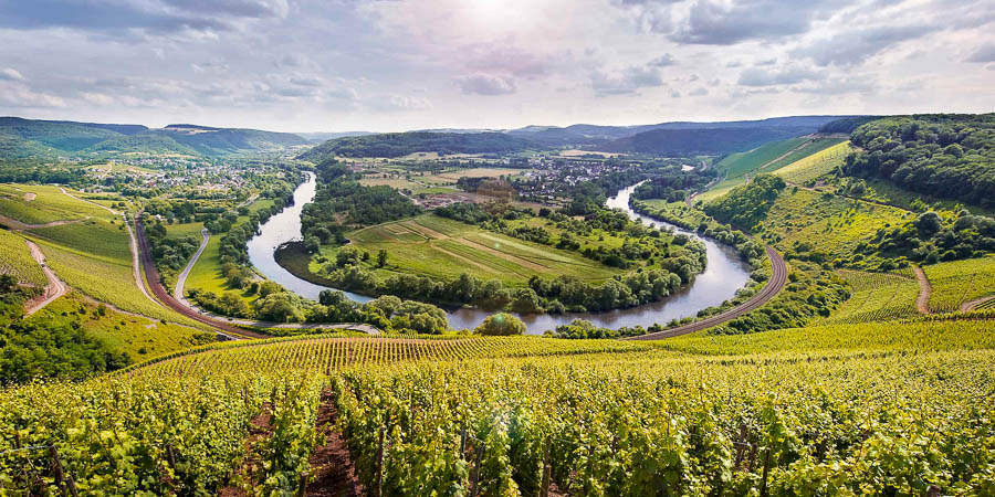 Weite Hügellandschaften sind mit einem Fluss im Saarland durchzogen